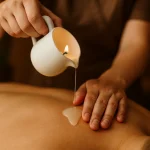نمای نزدیک از ریختن شمع داغ ماساژ روی پوست بدن