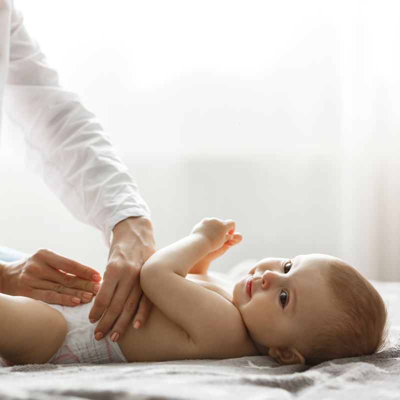 ماساژ آرام شکم نوزاد توسط مادر در محیطی روشن و آرام