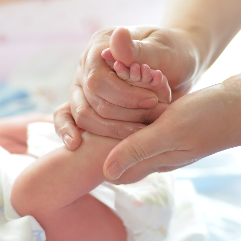 ماساژ آرام شکم نوزاد توسط مادر در محیطی روشن و آرام